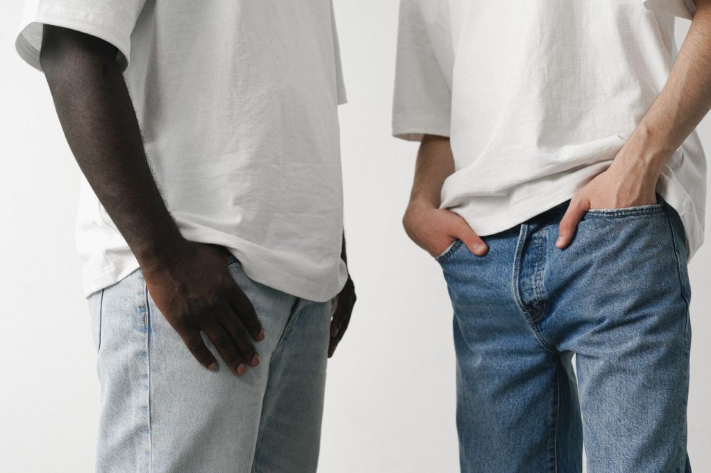 Close-up of two adults in white shirts and denim jeans, showcasing casual fashion style.